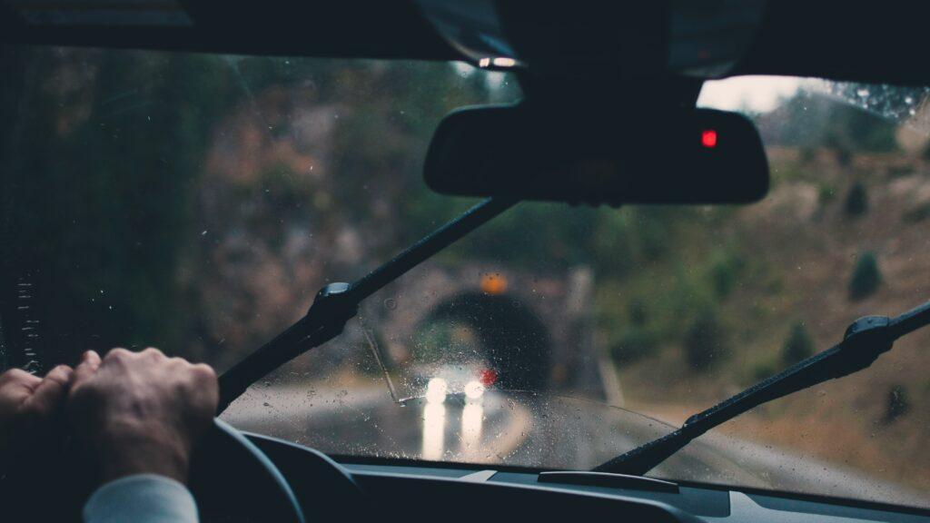 Conductor en un vehículo con visibilidad dificultada por la lluvia en el parabrisas.
